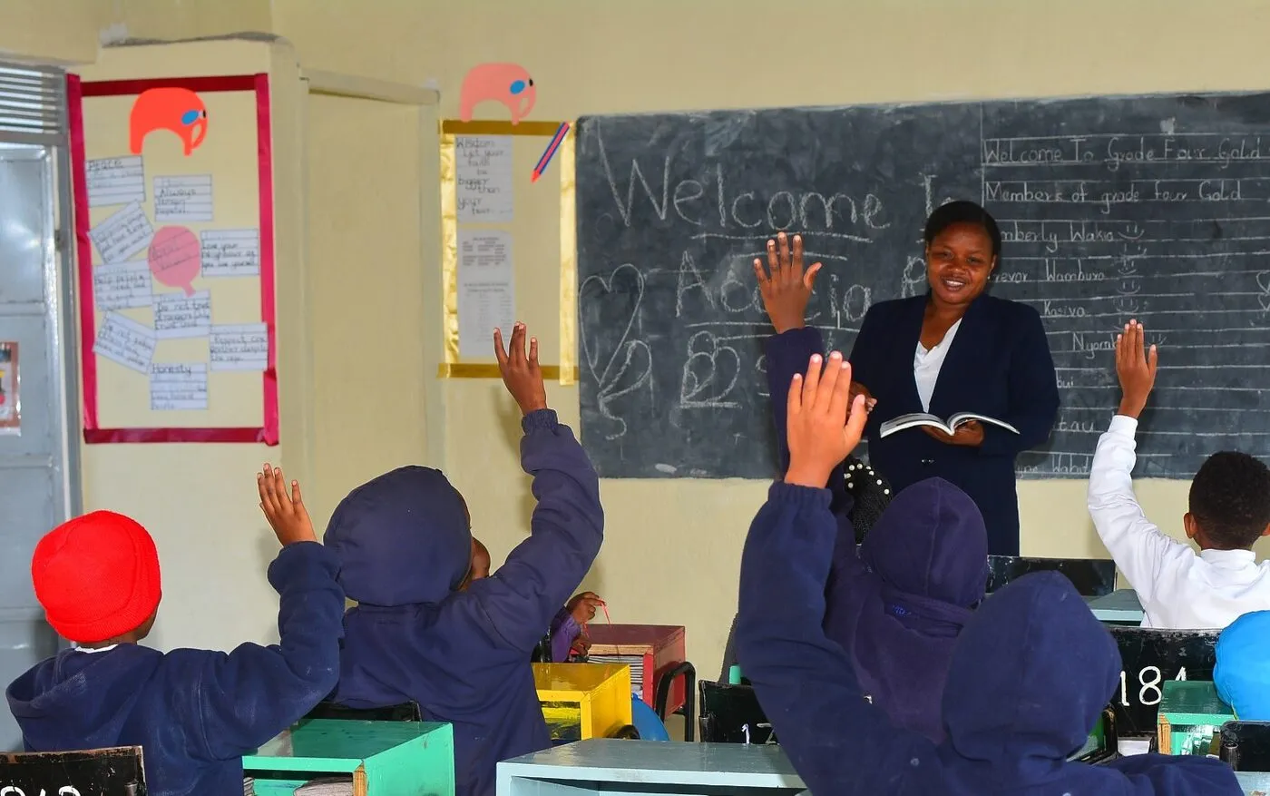 A teacher leading a lesson as pupils raise their hands